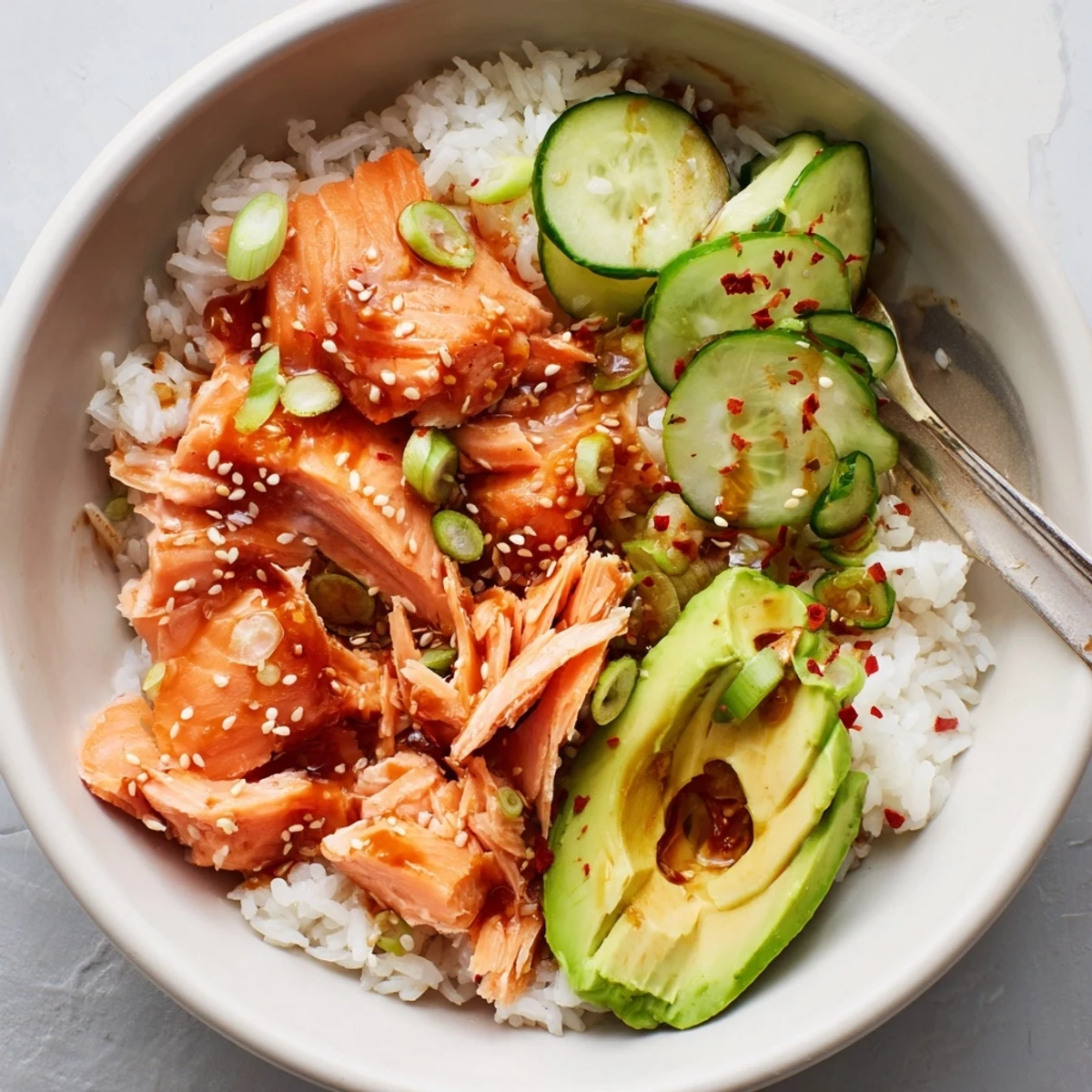 A vibrant Leftover Salmon & Rice Bowl showcasing fresh avocado and cucumber slices.  