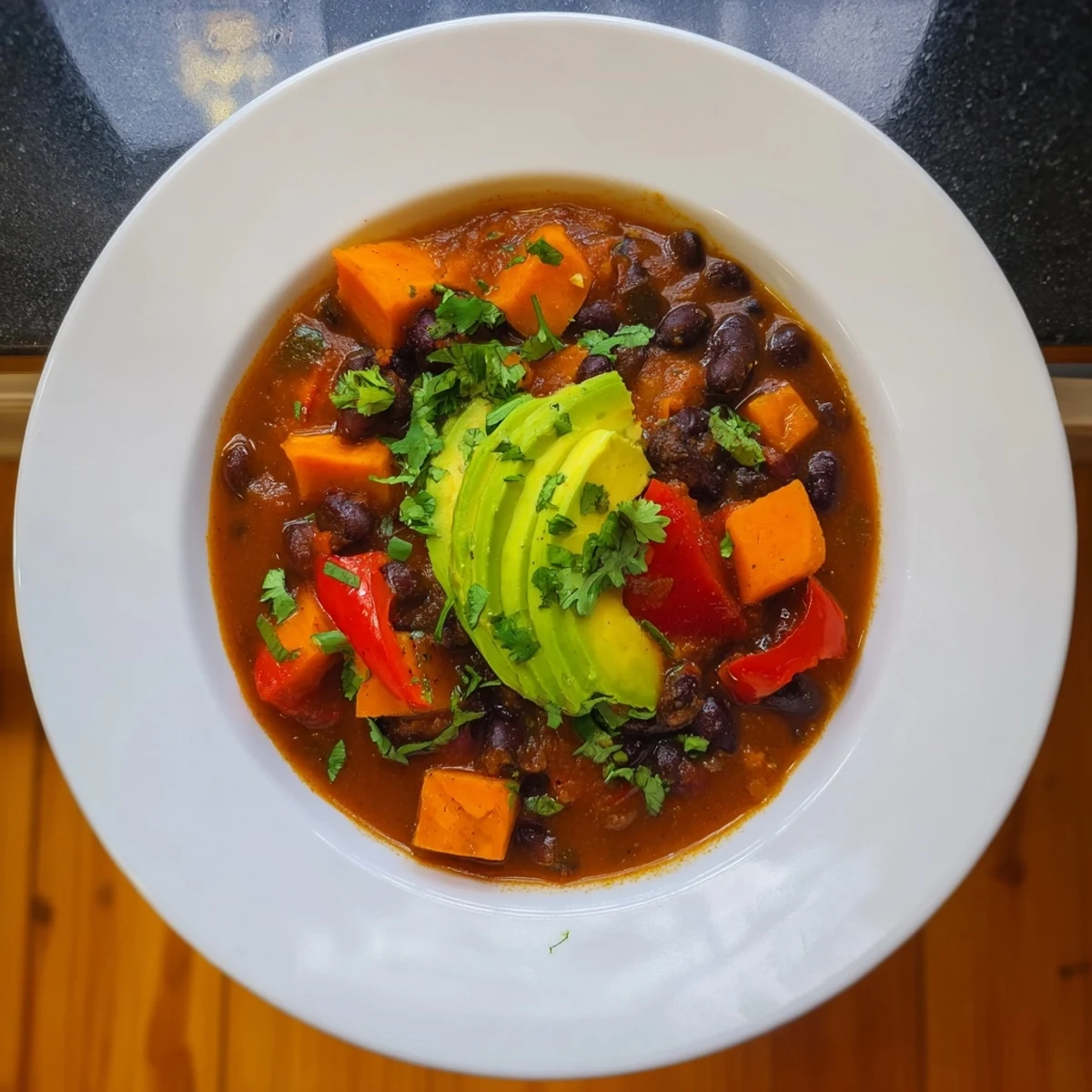Aromatic Sweet Potato & Black Bean Chili simmering with vegetables and savory spices in a pot.