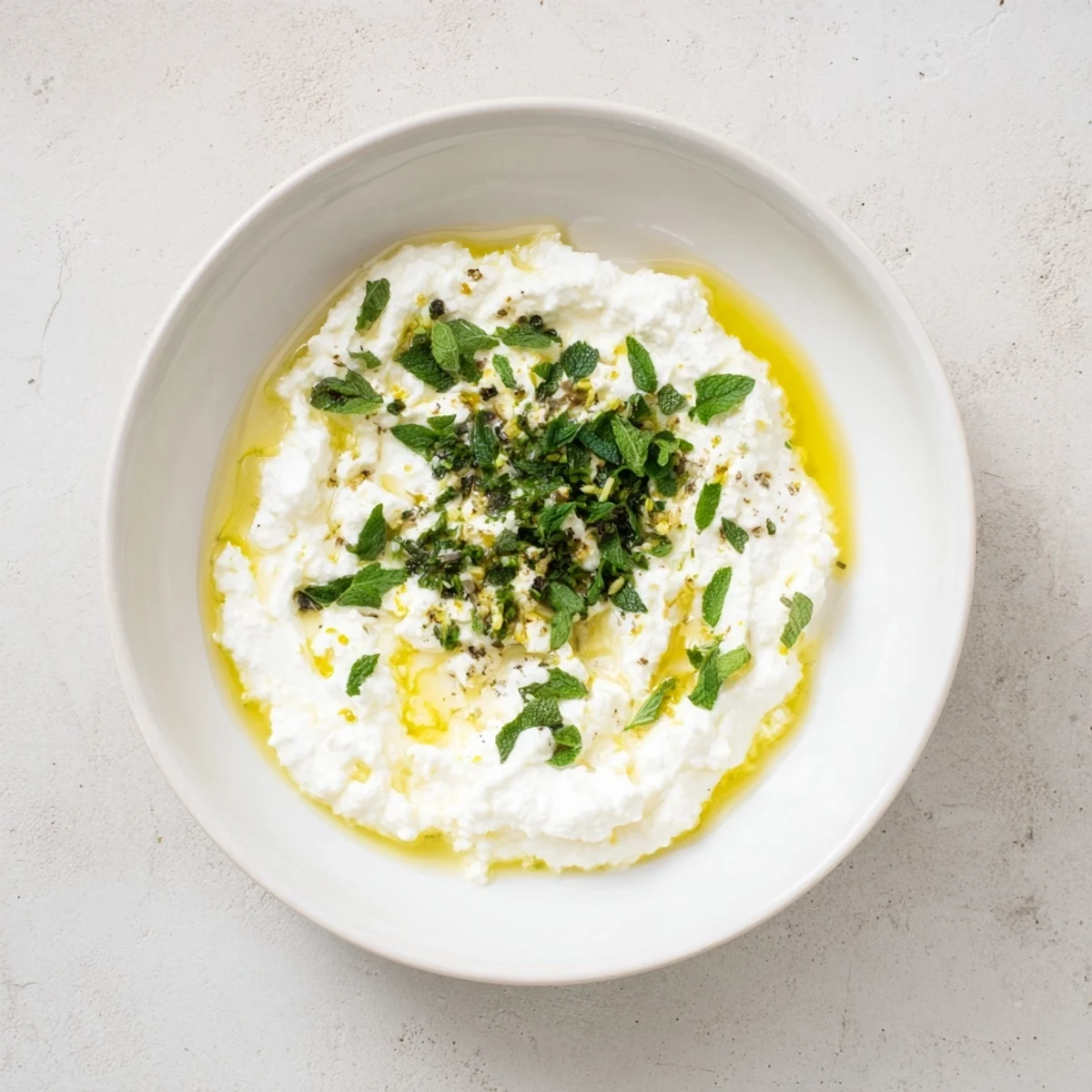 Creamy whipped feta dip with vibrant lemon-mint drizzle, ideal for dipping pita.