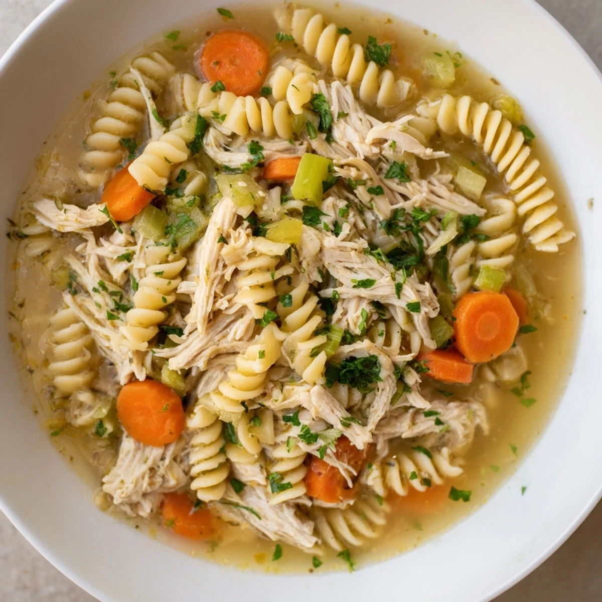 Warm, homemade Crockpot Chicken Noodle Soup, served with fresh parsley, looks and smells incredibly delicious.