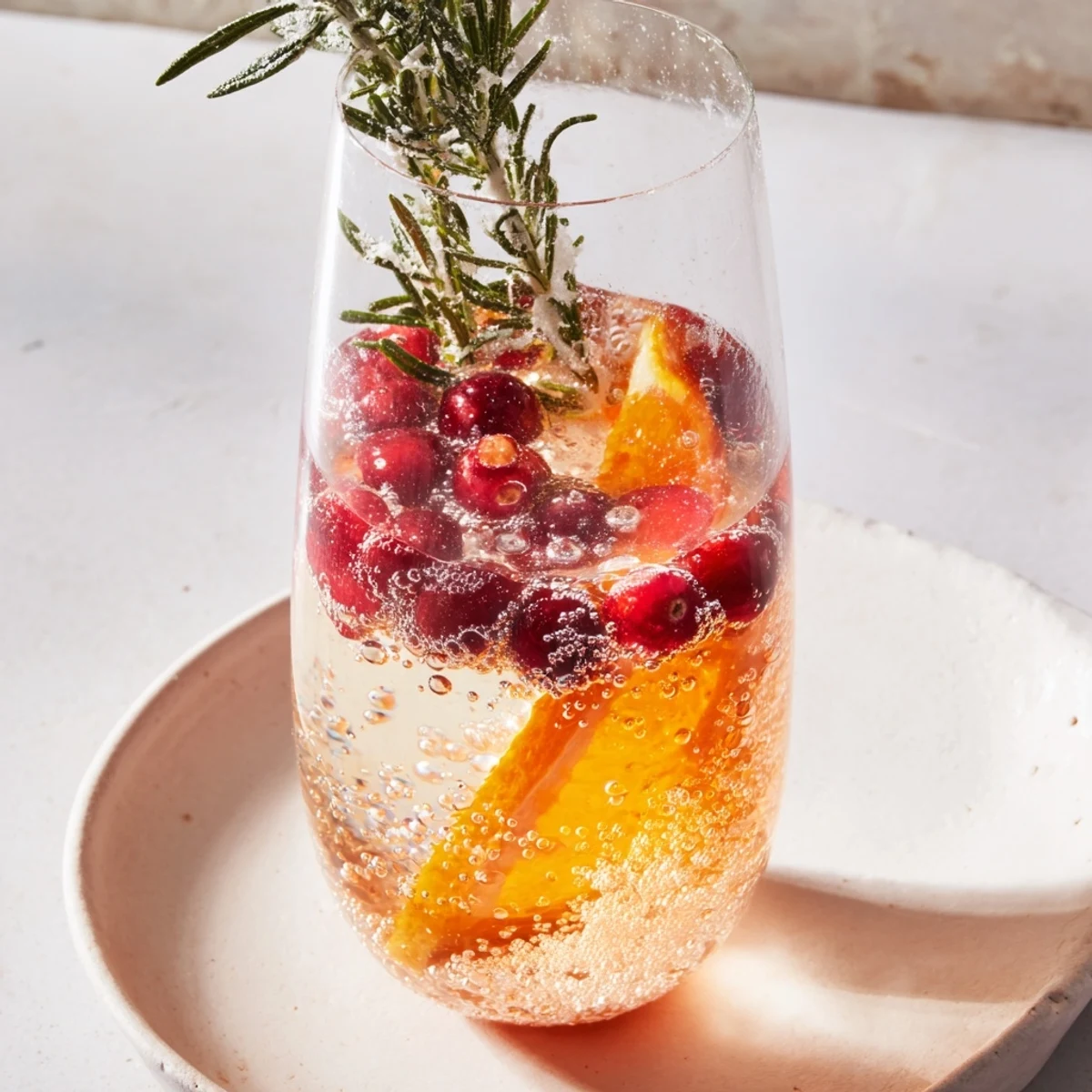 Sparkling Snow Globe Mocktail with vibrant orange slices and cranberries makes a beautiful, bubbly drink.