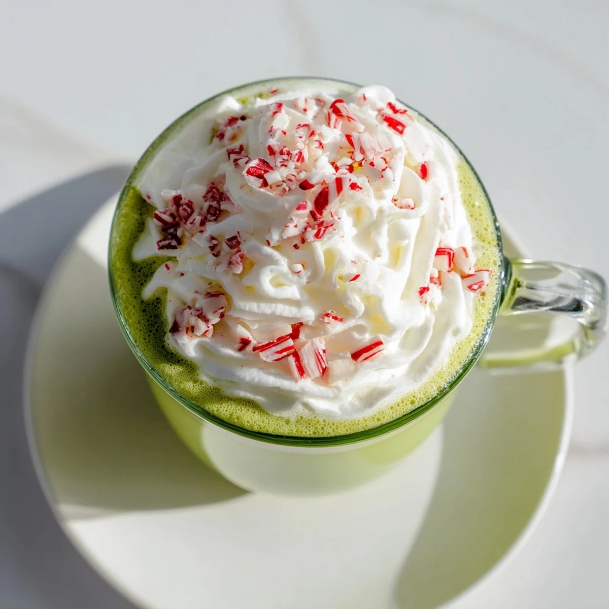 A vibrant mug of Cozy Peppermint Matcha Christmas Latte topped with sweet, fluffy whipped cream.