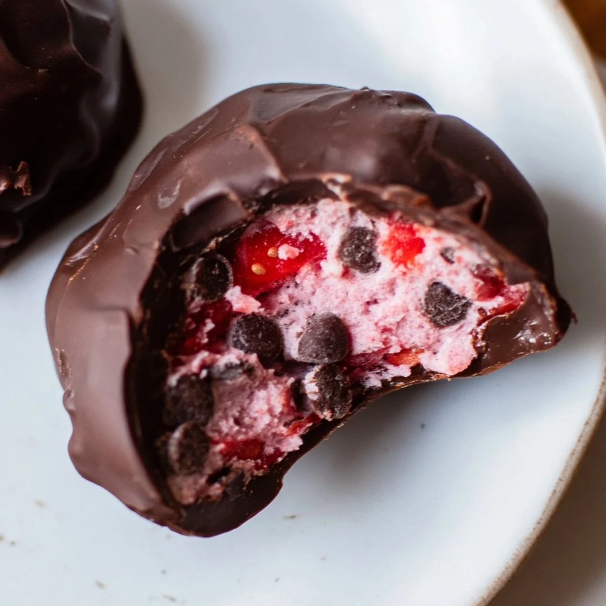 Strawberry Yogurt Clusters dipped in rich dark chocolate, a vibrant frozen treat.