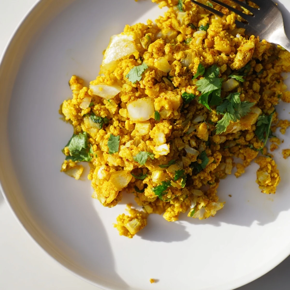 Vibrant turmeric cauliflower rice served warm as a side dish, topped with fresh parsley and lemon.