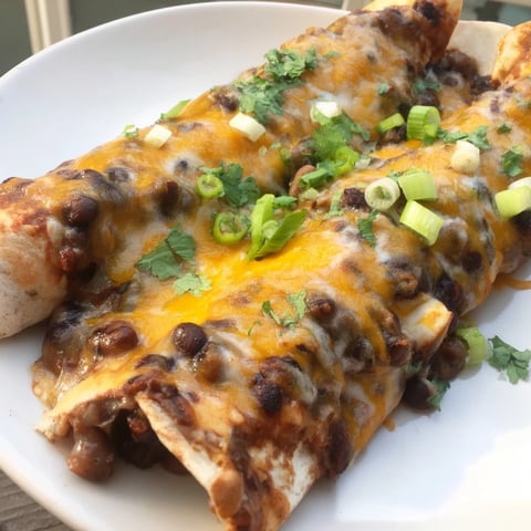 Mounds of melted cheese topping bubbly, saucy Cheesy Bean Enchiladas, a hearty Mexican meal.