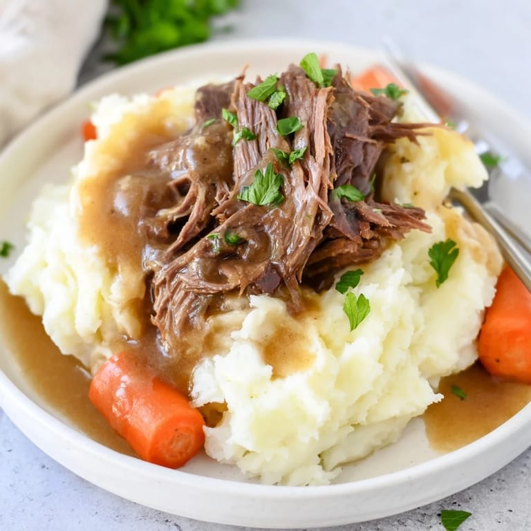 Tender slow-cooked pot roast accompanied by creamy mashed potatoes and hearty vegetables.  